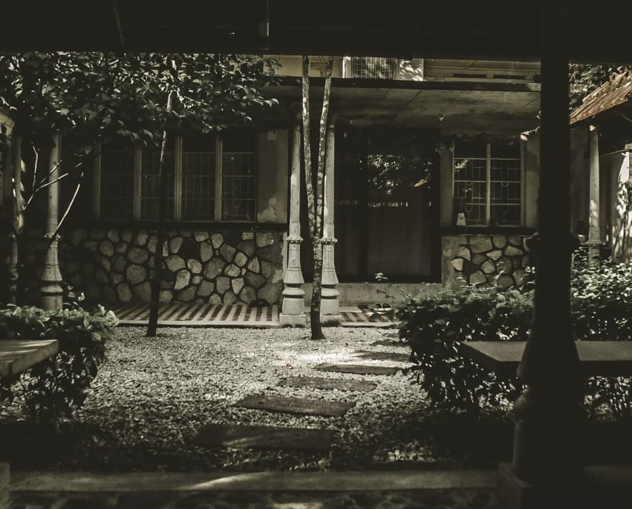 A quiet courtyard at home — stone walls, slender pillars, and a leaf-strewn path